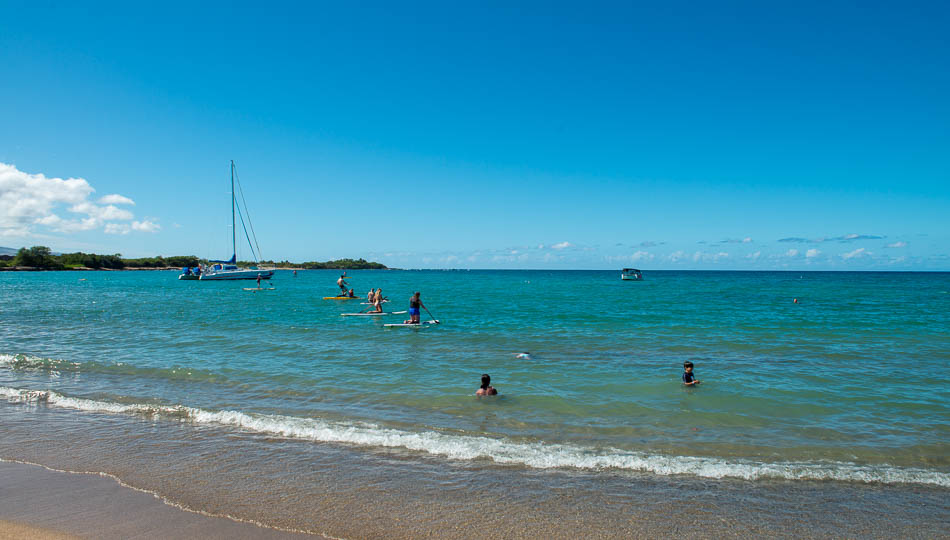 People Playing in the water and paddle boarding on Anaehoomalu Beach